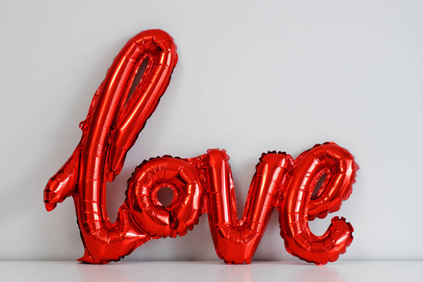 Liefde en Valentijnsdag concept - rode folie luchtballon liefde brieven over witte muur achtergrond - Foto, afbeelding
