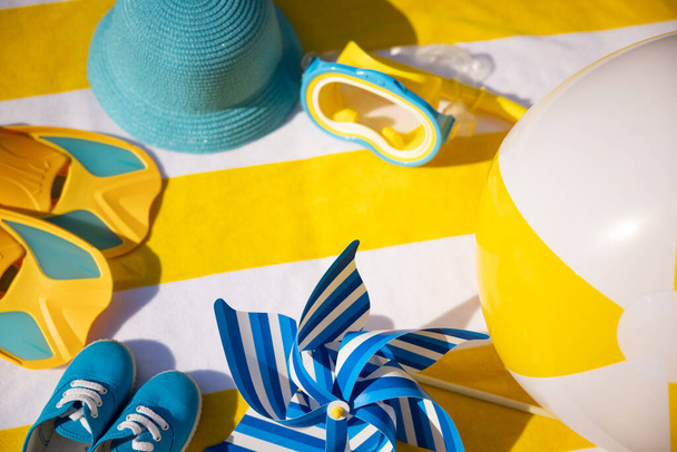 Beach accessories on yellow striped towel. Summer vacation concept - Photo, image