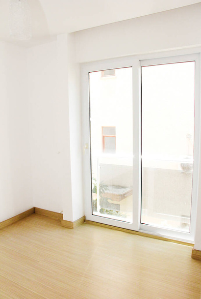 Ο σχεδιασμός του διαμερίσματος με λευκούς τοίχους, κίτρινο πάτωμα και διαφανή μεγάλα παράθυρα - Φωτογραφία, εικόνα