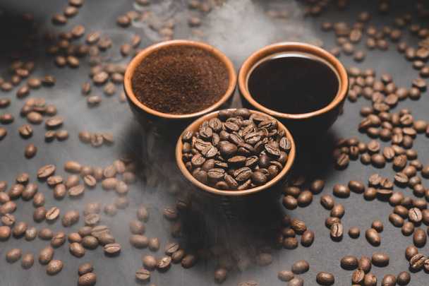 Coffee cups and roasted coffee beans on a black background in a pair, black coffee beans, ground and freshly brewed. - Photo, Image