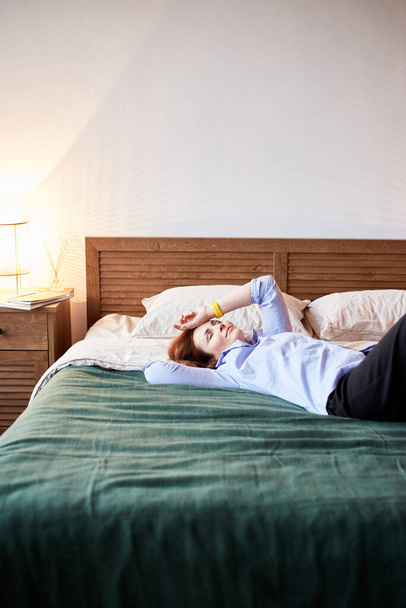 Cozy portrait of millennial female  relaxing on cozy bed. Bedroom with modern interior - Foto, afbeelding
