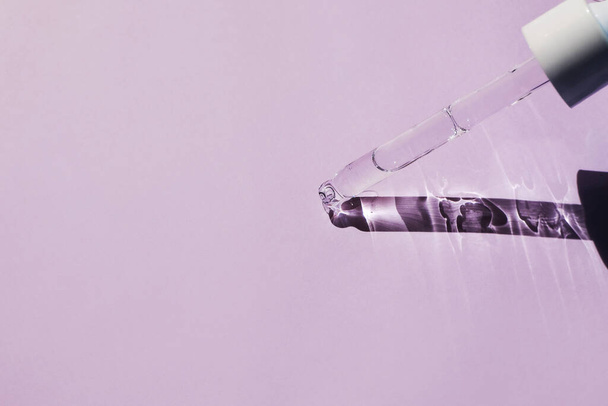 Glass pipette with aloe vera gel on a pink background. Side view, space for text. - Photo, Image