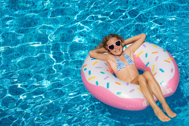 Happy child swimming in outdoor pool. Girl having fun on summer vacation. Healthy lifestyle concept - Foto, imagen