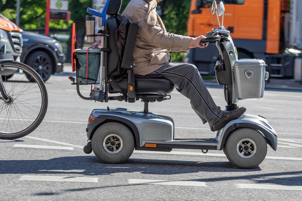 літня людина на електричному інвалідному візку їде на вулиці
 - Фото, зображення