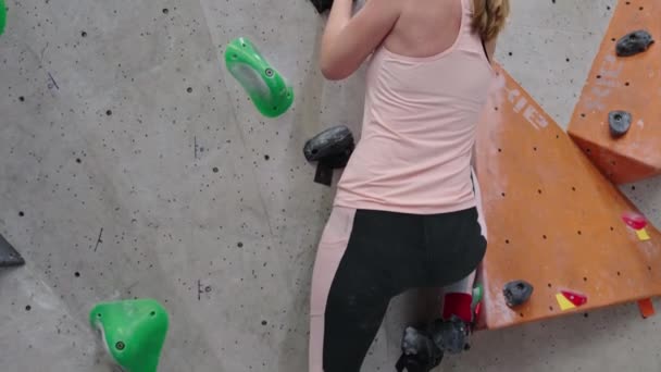 Woman climbing up on wall at bouldering gym. Female climber training, hanging on bouldering climbing wall. Active lifestyle and extreme sport concept. - Footage, Video
