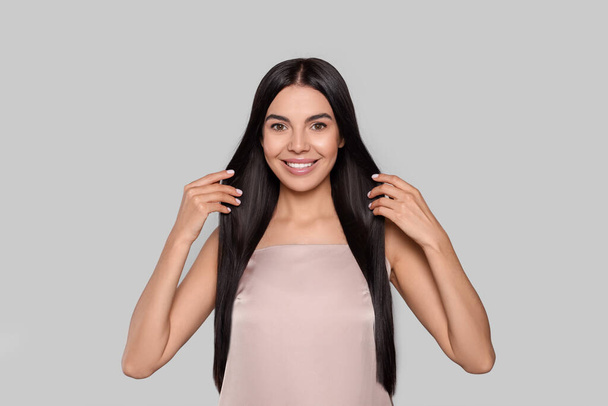 Portrait of beautiful young woman with healthy strong hair on light grey background - Φωτογραφία, εικόνα