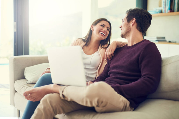 Hätte man sich keine bessere Art und Weise wünschen können, den Tag zu verbringen. ein fröhliches junges Paar, das einen Laptop benutzt, während es sich zu Hause auf dem Sofa entspannt - Foto, Bild