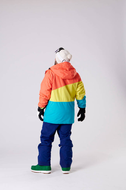 Chlapec na zádech s kloboukem, rukavicemi, boty a snowboardové oblečení na bílém pozadí. - Fotografie, Obrázek