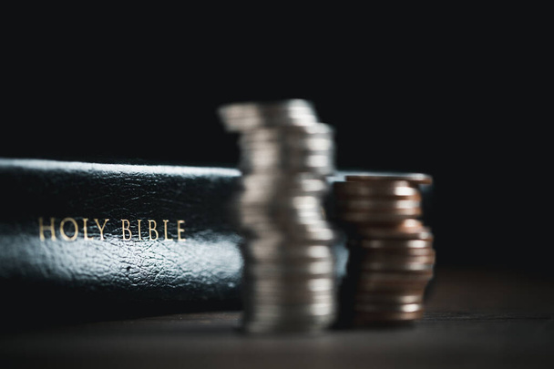 One tenth or tithe is basis on which Bible teaches us to give one tenth of first fruit to God. coins with Holy Bible. Biblical concept of Christian offering, generosity, and giving tithes in church. - Photo, Image