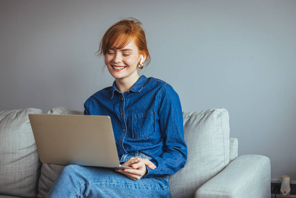 young woman with laptop and glasses sitting on sofa at home  - Foto, imagen