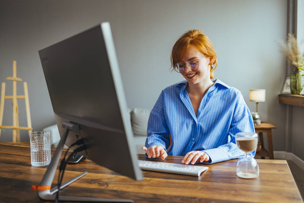 молодая работница занята работой над компьютером, печатая деловое письмо клиенту - Фото, изображение
