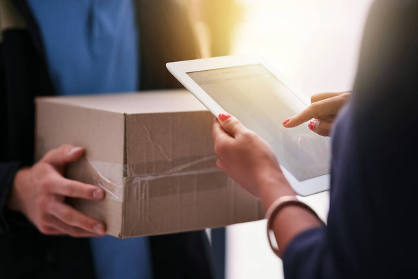 Make paperwork a thing of the past. an unidentifiable businesswoman using a tablet to sign for a package delivered to her office - Photo, Image