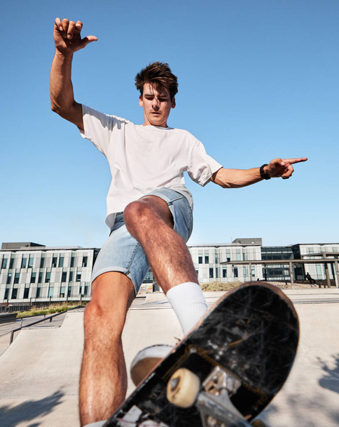 Skateboard, ciudad y deportes con un hombre al aire libre en verano para la recreación o la diversión mientras patina solo. Calle, patinador y energía con un joven monopatín masculino o montando una tabla en una ciudad urbana. - Foto, imagen