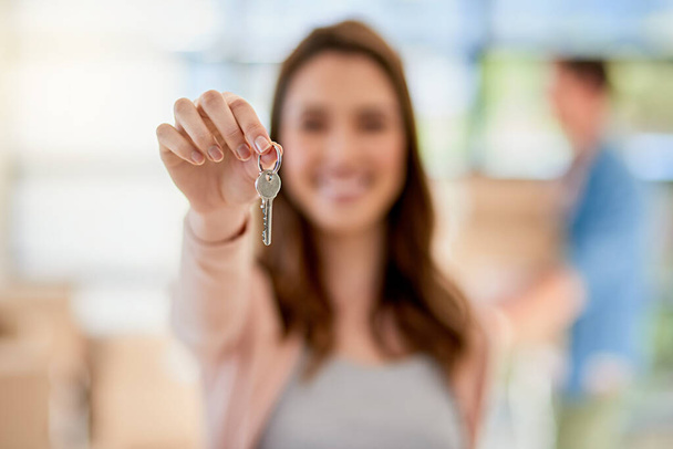 A chave para abrir uma nova vida. Retrato de uma jovem mulher segurando as chaves de uma nova casa com seu namorado no fundo - Foto, Imagem