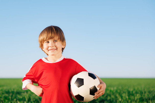 Happy kid pretend to be a soccer player. Portrait of child outdoor. Boy against green field. Success and winner concept - Photo, Image