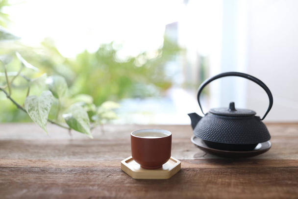 cserépedény teáscsésze és teáskanna fa asztalon szabadtéri relaxáció ivás - Fotó, kép