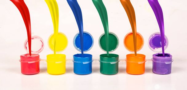 Splash of multi colors pouring into paint buckets isolated white background. - Photo, Image