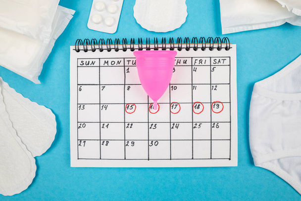 Vista superior de la foto de toallas sanitarias, calendario de señoras con marcas en el fondo azul aislado. El concepto de los períodos de la mujer. - Foto, imagen
