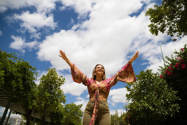 Woman smiling arms raised up to blue sky, celebrating freedom. Positive human emotions, face expression feeling life perception success, peace of mind concept. Free Happy girl on park enjoying nature - Foto, afbeelding