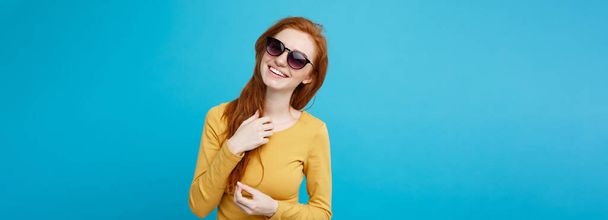 Travel concept - Close up Portrait young beautiful attractive ginger red hair girl with trendy sunglass smiling. Blue Pastel Background. Copy space - Photo, Image