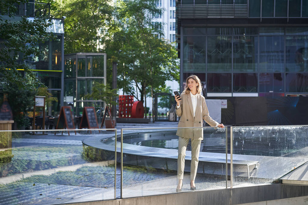 Femme d'affaires confiante en costume beige, debout au pouvoir pose dans le centre-ville. - Photo, image