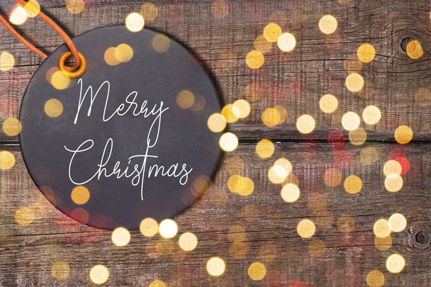 merry christmas tag on wood table with bokeh background - Photo, Image