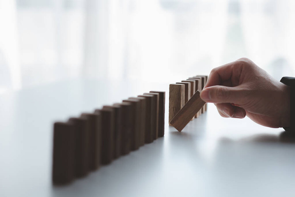 A close-up shot of a businessman holding the wooden blocks in a row, the wood blocks compare to the business risk management. The concept of risk management. copy space. - Photo, Image