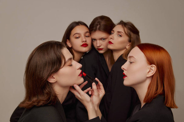 Portrét mladých krásných žen v černých bundách a červené rtěnky make-up pózovat na šedém pozadí. Příprava. Koncept krásy, svobody, emocí, mimořádné módy, moderního stylu, mládeže - Fotografie, Obrázek