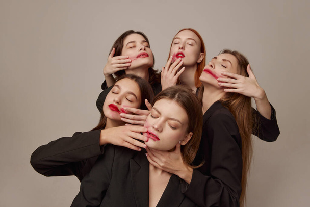 Portrait of young beautiful women in black jackets and red lipstick posing over grey background. Smeared makeup. Concept of beauty, freedom, emotions, extraordinary fashion, modern style, youth - Photo, Image