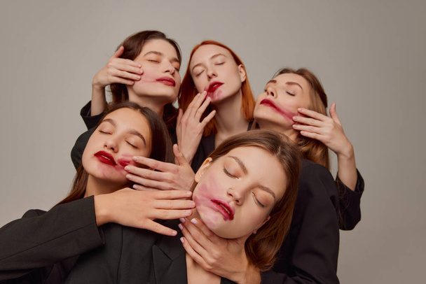 Portrait of young beautiful women in black jackets and red lipstick makeup posing over grey background. Party is over. Concept of beauty, freedom, emotions, extraordinary fashion, modern style, youth - Foto, imagen