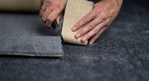 Handyman cutting a new carpet with a carpet cutter..	 - Photo, image