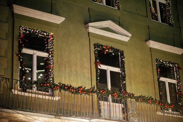 Elegantes ramas de abeto navideño con adornos y luces festivas en el exterior del edificio por la noche. Decoración moderna de Navidad en la calle de la ciudad. Vacaciones de invierno en Europa. Feliz Navidad. - Foto, Imagen