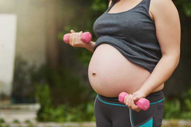 Madre en entrenamiento. una mujer embarazada irreconocible haciendo ejercicio al aire libre - Foto, imagen
