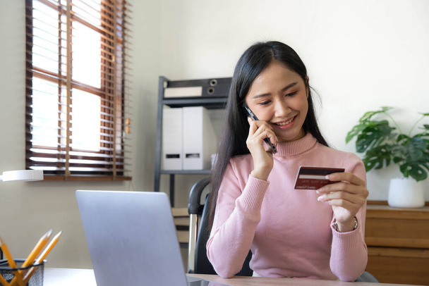 Щаслива азіатська бізнес жінка платить онлайн за допомогою мобільного телефону вдома
 - Фото, зображення