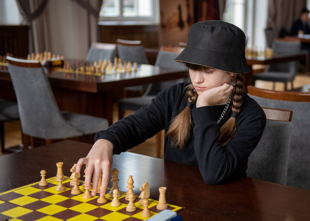 The girl plays chess. Pieces on the chessboard. Chess game, close-up, portrait. Chess tournament, competition - Photo, Image