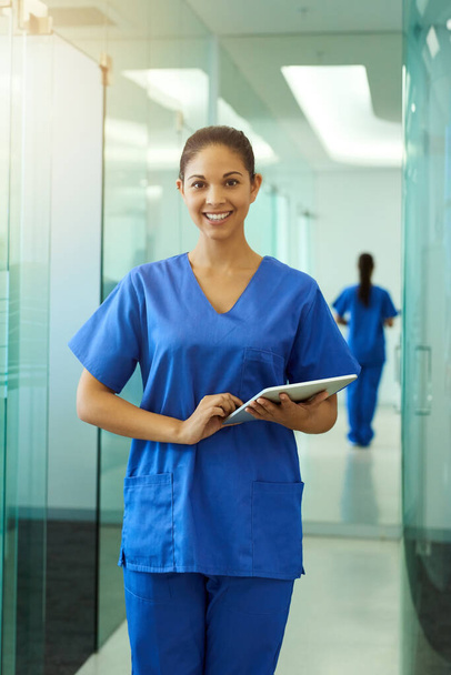 Healthcare is what I was meant for. Portrait of a young nurse using a tablet while standing inside a clinic - Foto, imagen