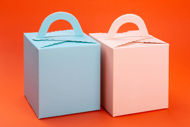 pink and turquoise gift boxes stand side by side on orange background, concept of holiday gifts - Φωτογραφία, εικόνα