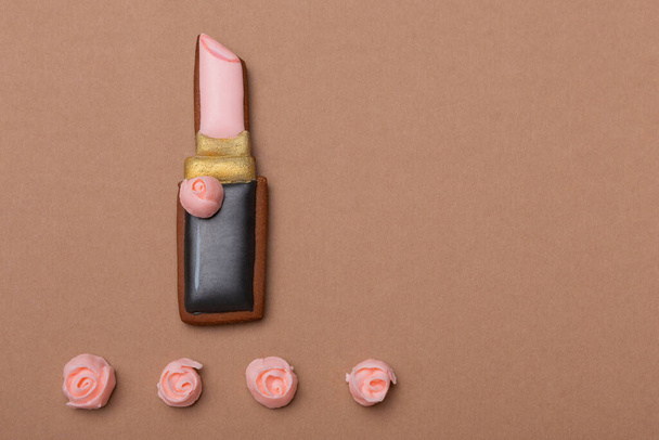 gingerbread in the form of lipstick for lips on a brown background, the concept of a holiday and gifts, copy space - Φωτογραφία, εικόνα