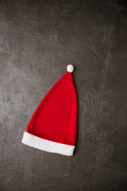 Red Santa Claus hat on a gray background. Christmas concept - Photo, Image