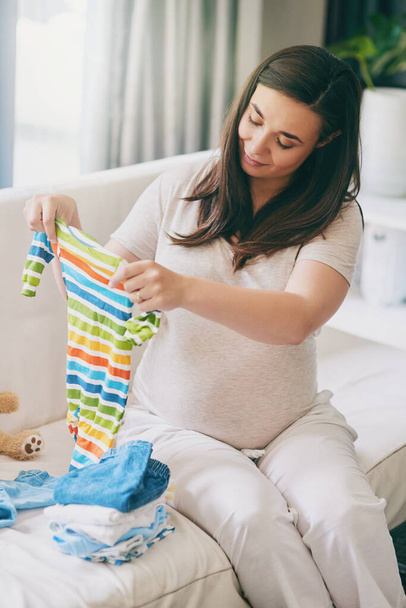 Hell look so handsome in this. a pregnant woman sorting baby clothes - Photo, Image