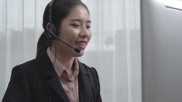 Ázsiai ügyfélszolgálat fülhallgatót és mikrofont visel, laptoppal dolgozik az asztalánál. Lelkes női alkalmazott nyújt ügyfélszolgálatot, támogató call center ügynök segít az ügyfeleknek. - Felvétel, videó