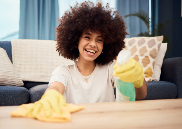 Šťastná, portrétní a černá žena čistí prach na stolním nábytku hadříkem, tekutým mýdlem ve spreji a rukavicemi. Čistič, úklidové služby a africká dívka setře špinavý nebo špinavý povrch. - Fotografie, Obrázek
