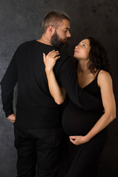 Una mujer embarazada con un hombre sobre un fondo oscuro - Foto, Imagen