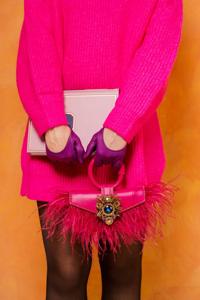 Fashionista im rosa Pullover, Lederhandschuhe mit rosa Tasche mit Straußenfedern - Foto, Bild
