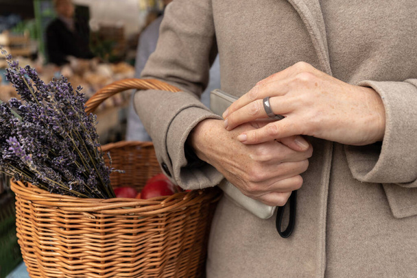 Nainen tuli ruokakauppaan ostoksille ja piteli käsilaukkua ja koria laventeli ja omenat käsissään. Laadukas kuva - Valokuva, kuva