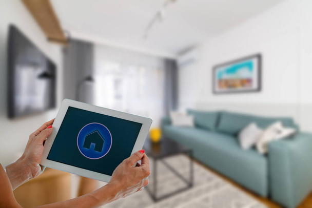 Smart Home App on a Tablet. Woman Controlling Appliances at Home. - Fotografie, Obrázek