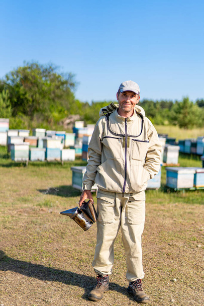 Man in protective beekeeping suit in apiary. Summer honey farming apiarist. - Valokuva, kuva