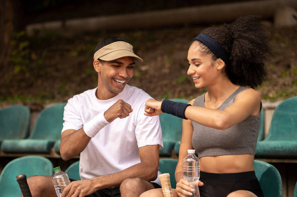 Discussing the game. Young man and woman sitting at the tennis court and discussing the game - Foto, Imagen