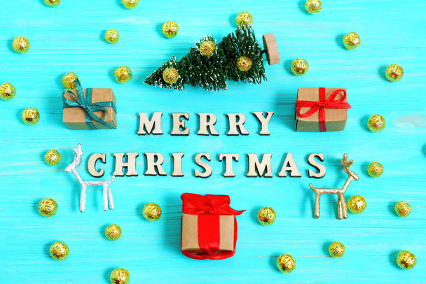 Vivid happy Holidays advertising campaign background with toy Christmas tree, deer figurines, decoration balls and wrapped gift-boxes on a blue wooden background. - Foto, Imagem