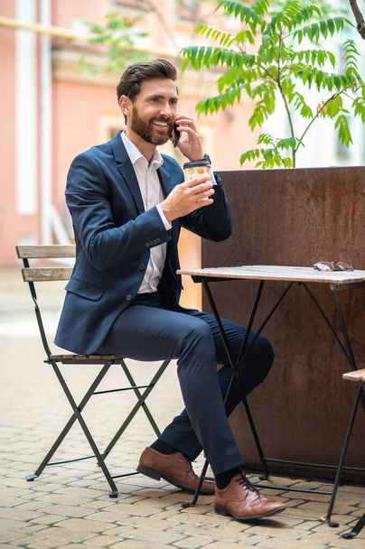 Coffee break. Young handsome businessman having coffee in a street cafe - 写真・画像